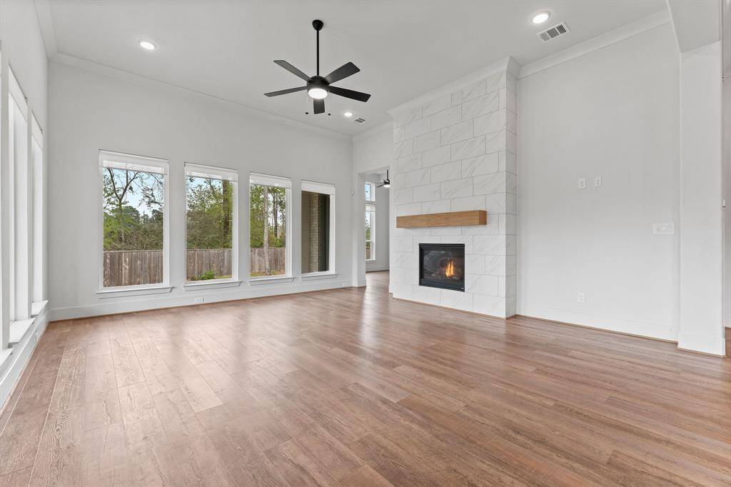 At its heart, a stately floor-to-ceiling gas log fireplace—framed in tasteful tile and topped with a classic wood mantle—adds warmth and sophistication. Crown molding, recessed lighting, and a lighted ceiling fan enhance the room’s timeless appeal.