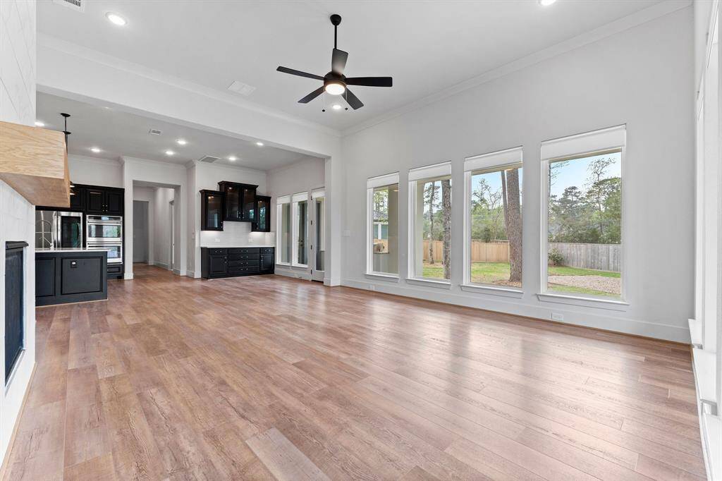 Seamlessly connected to the kitchen, the open-concept layout fosters easy conversation and effortless entertaining. Rich wood-look vinyl plank flooring flows throughout, tying the space together with warmth and continuity. This spacious and sun-filled family room truly embodies comfortable luxury.