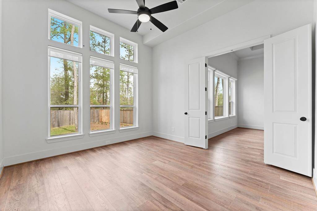 This spacious great room off the Family room offers incredible versatility with its three floor-to-ceiling windows, complemented by elegant transoms. The room features durable vinyl plank flooring, cordless solar shades for natural light control, and a lighted ceiling fan to keep the space comfortable. It provides access to the Owner’s suite through double doors, as well as to the private covered porch, making it an ideal spot for relaxation.