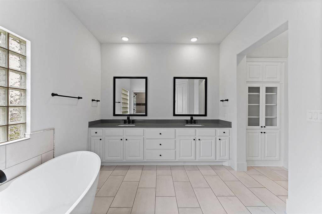 Framed mirrors and gleaming quartz countertops on the double vanities add sophistication, with extra vanity space in between to ensure plenty of room for your morning routine. This en suite is truly a soothing sanctuary.