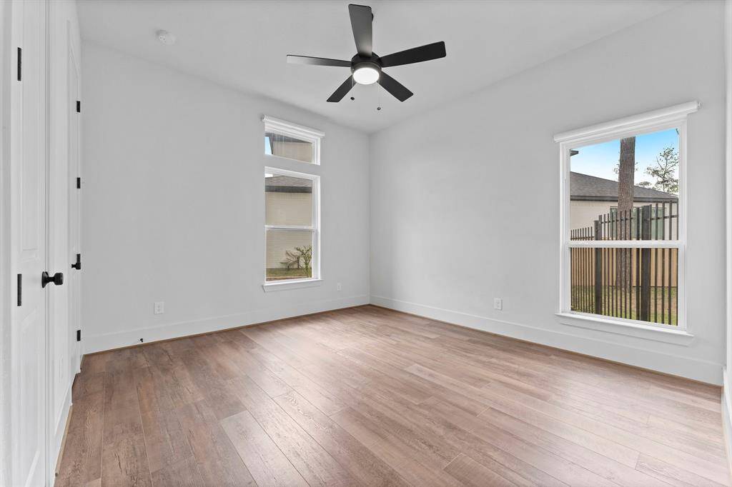 A charming secondary bedroom on the first floor is located at the front of the home, offering privacy away from the Owner’s suite. This cozy room features wood-look vinyl plank flooring, a spacious wall closet, and two large windows that allow plenty of natural light to brighten the space. The windows are equipped with cordless room-darkening shades, perfect for a restful sleep. A lighted ceiling fan adds comfort and style. The room has convenient access to a full bath, which is shared with Bedroom 3.