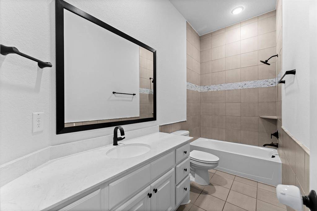 2nd full bathroom for Bedrooms 2 and 3 includes single sink, quartz countertop, tile flooring, recessed lights, framed mirror, toilet, and tiled shower/tub combo.