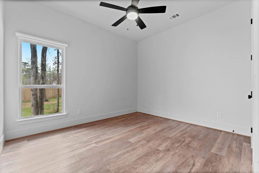 A secondary bedroom on the first floor is located in the front of the home away from the Owner’s suite and offers wood-look vinyl plank flooring, large walk-in closet, sunny window with cordless room-darkening shade, and lighted ceiling fan. It has hallway access to a full bath shared with Bedroom 2.