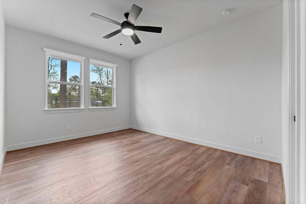 A secondary bedroom on the second floor offers wood-look vinyl plank flooring, large walk-in closet, two sunny windows with cordless room-darkening shades, and lighted ceiling fan. It has hallway access to a full bath shared with Game Room guests.