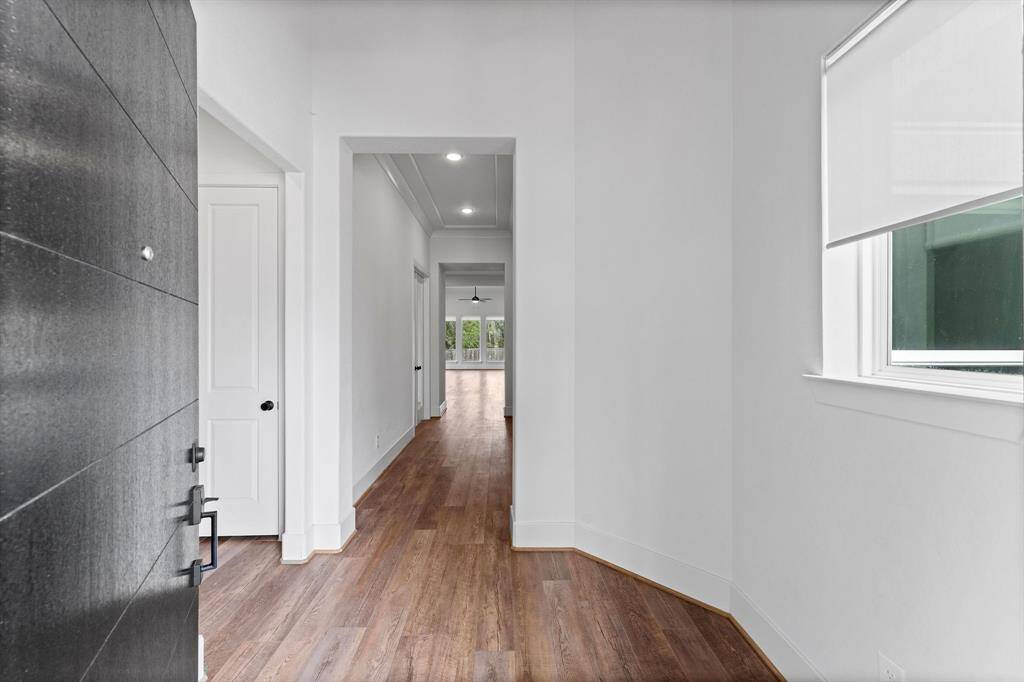 Step into a foyer that exudes warmth and timeless sophistication, where every detail has been thoughtfully curated. Rich wood-look vinyl flooring, a classic tray ceiling, and an elegant chandelier set the tone, complemented by custom wood trim and impeccable moldings. A spacious layout offers room for an entry table or bench, while a sunlit window brings in natural light and charm. A guest coat closet adds both convenience and function to this graceful entryway.
