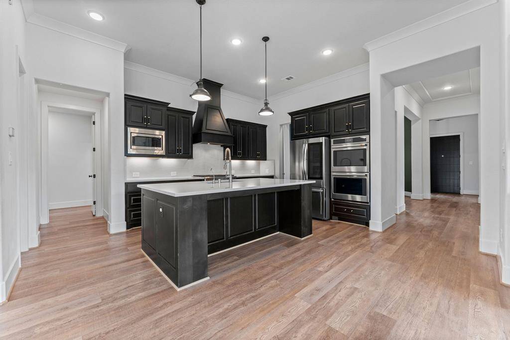Designed for the discerning chef, this exceptional kitchen offers both style and functionality in every detail. A spacious island provides additional storage, ample workspace, and inviting breakfast bar seating. Striking Cambria quartz countertops elevate the space, complemented by a seamless quartz backsplash and under-cabinet lighting for a sophisticated, polished look.