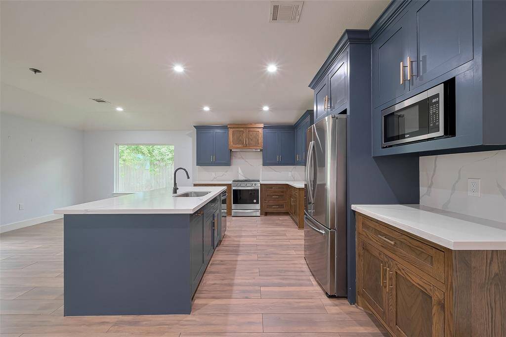 Stylish open kitchen featuring quartz countertops and stainless-steel appliances.