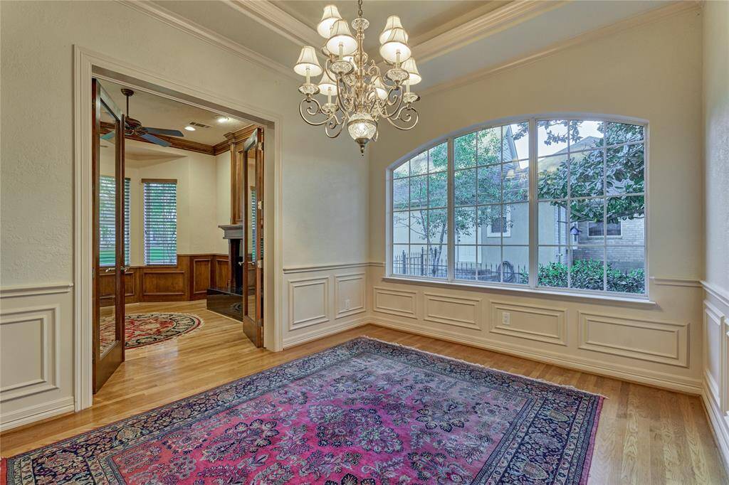 Elegant double French doors open into a cozy sitting room with charming front yard views.