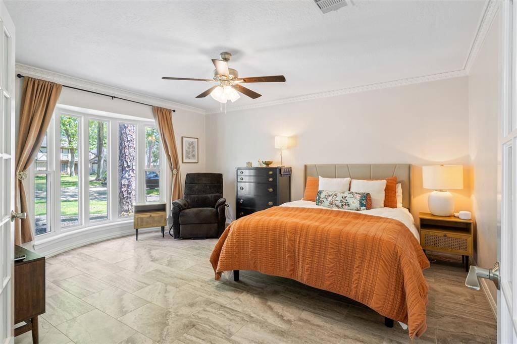 Bright and spacious room downstairs with large bay windows, neutral walls, and gorgeous tile flooring.