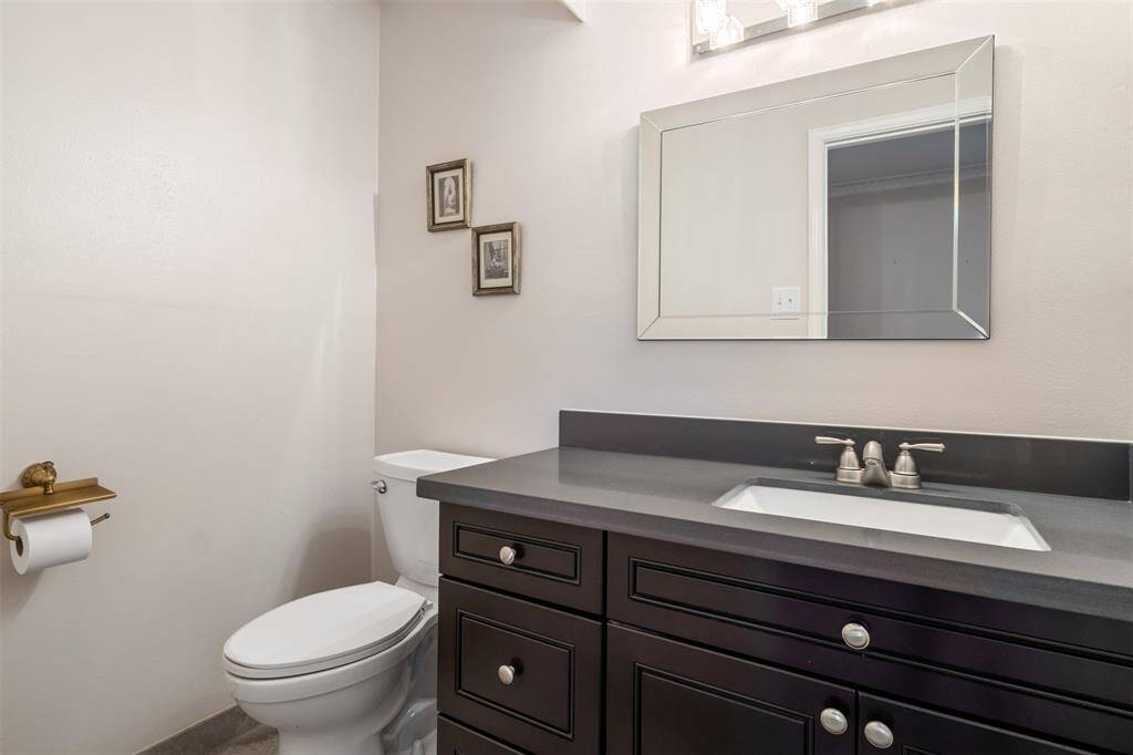 This bathroom features a modern design with a sleek dark vanity, a rectangular mirror, and neutral wall tones. The elegant lighting, creates a clean and inviting space.