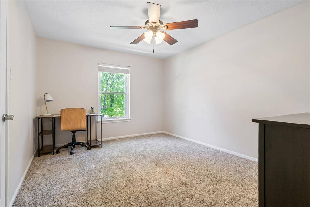 Upstairs secondary carpeted bedroom with neutral walls features a ceiling fan and a window offering lots of natural light.