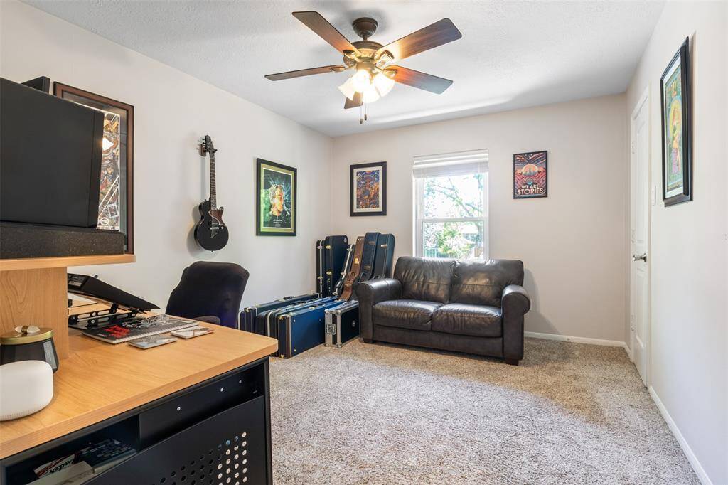 This room is a cozy, carpeted space perfect for a bedroom, home office or music room. It features a ceiling fan, ample natural light from a window and large walk in closet for plenty of storage.