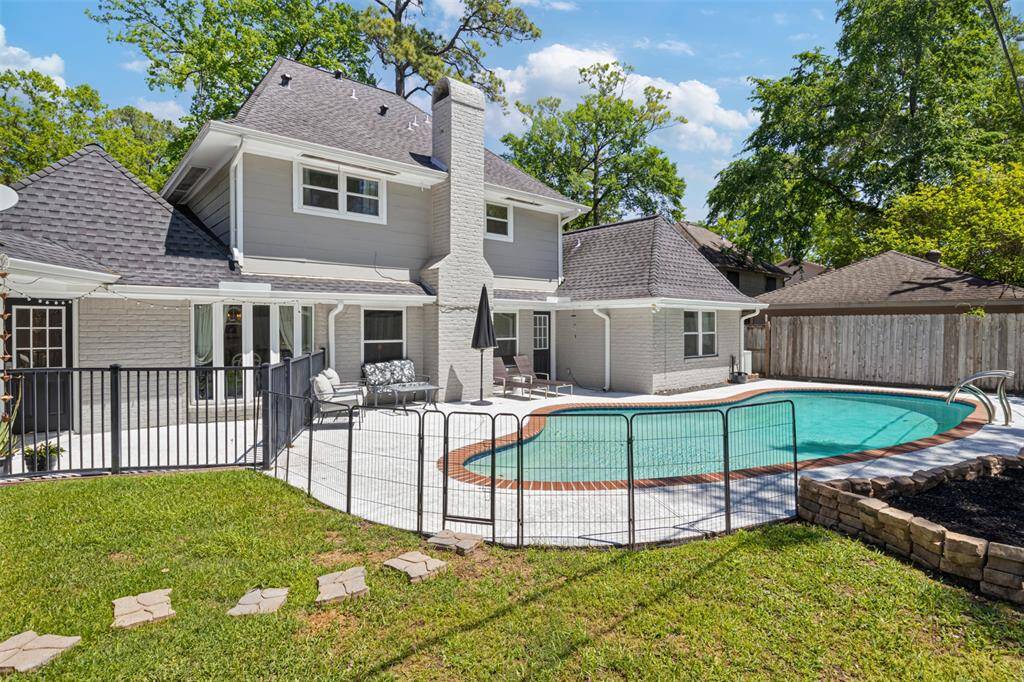 This charming two-story home features a spacious backyard with a fenced-in pool, perfect for entertaining. The exterior is well-maintained with a light gray facade, surrounded by mature trees providing privacy and shade.