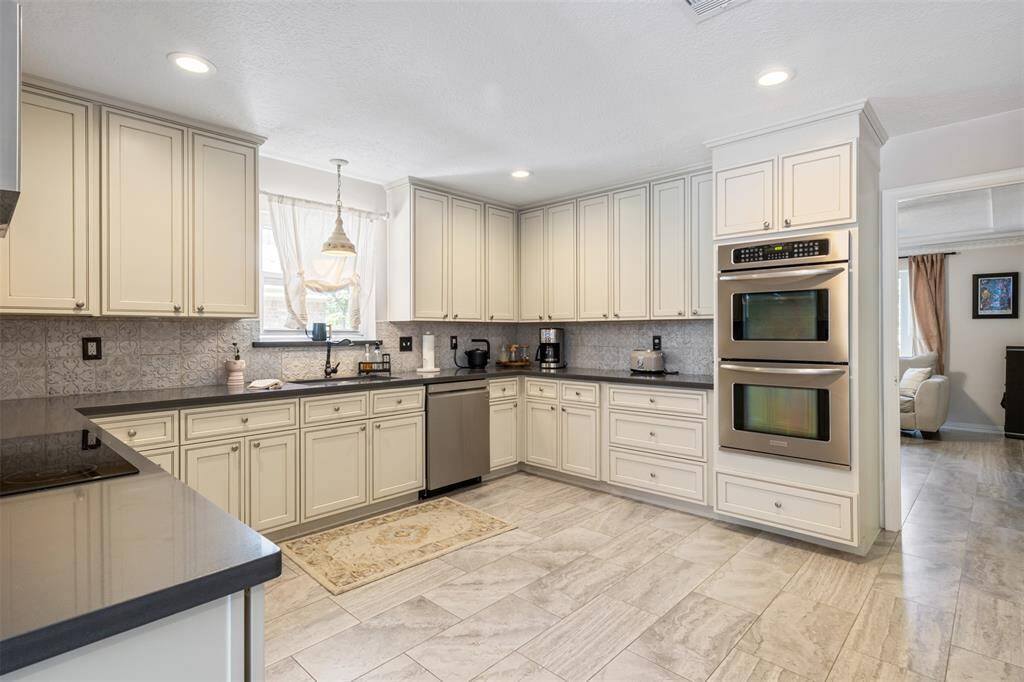 This beautiful and modern kitchen features lots of storage and ample counter space. The room is well-lit with recessed lighting and a window above the sink, offering a spacious and inviting environment for cooking and entertaining.
