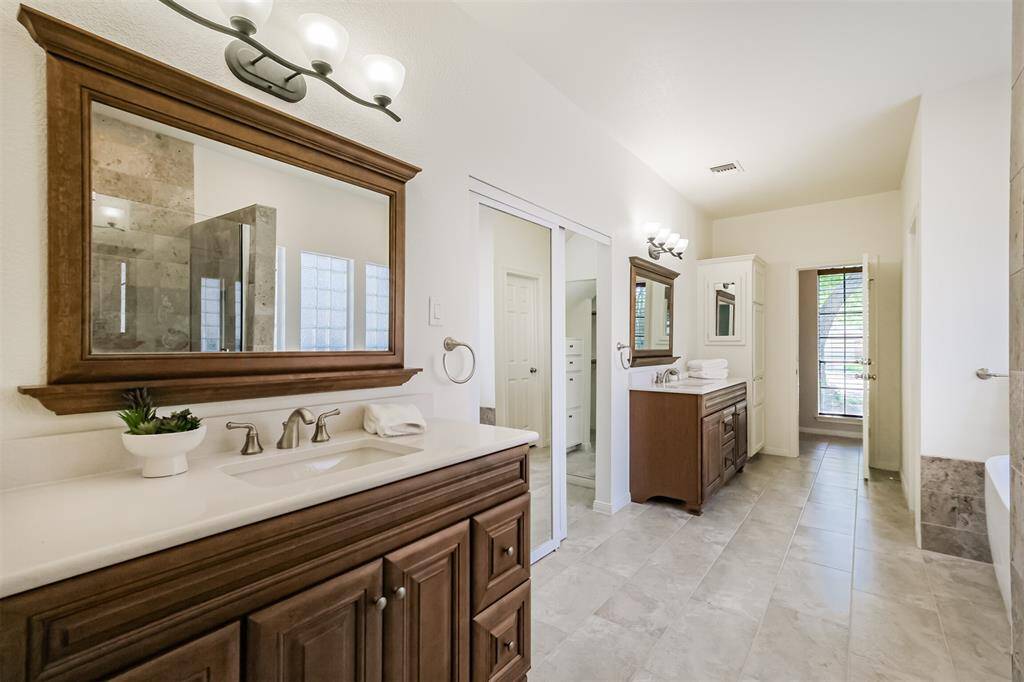 the luxurious primary bathroom was completely remodeled from the studs up in 2025 and boasts double vanities, new mirrors, tiled flooring and lighting.