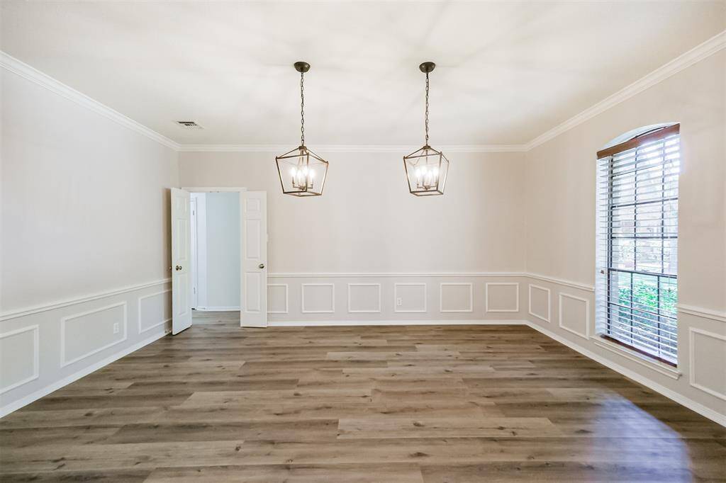 The Formal Dining Room with Crown Molding, detailed wainscoting and new pendant lighting is located to the right as you enter the home. The double doors lead directly to the kitchen.
