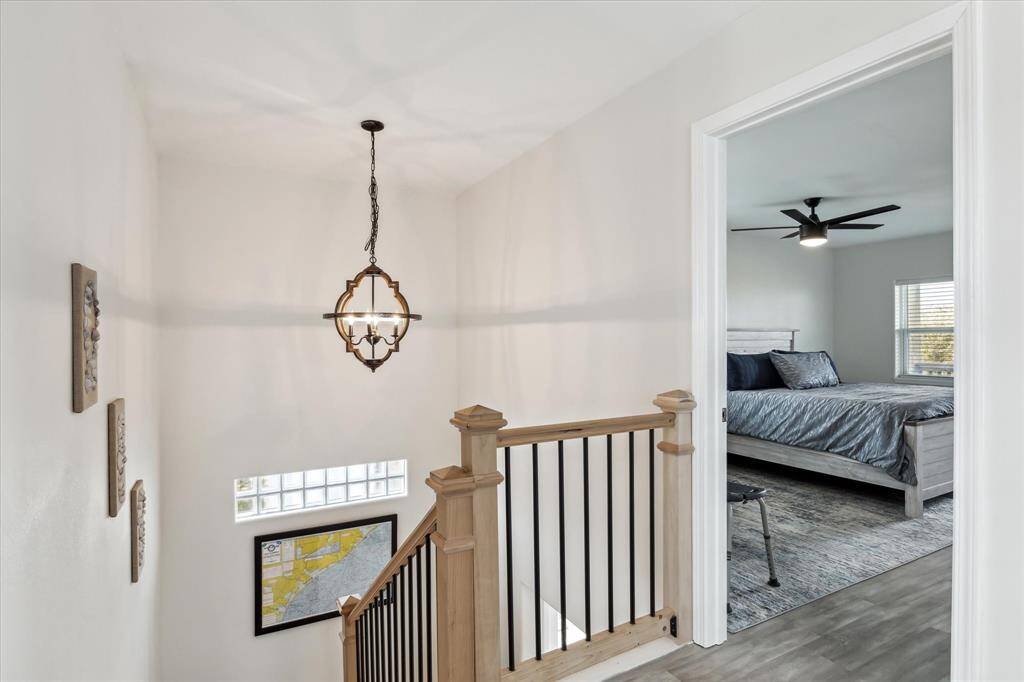 Fully furnished with artwork and everything!  This photo showcases a bright and airy upstairs landing with modern railing and a stylish light fixture.