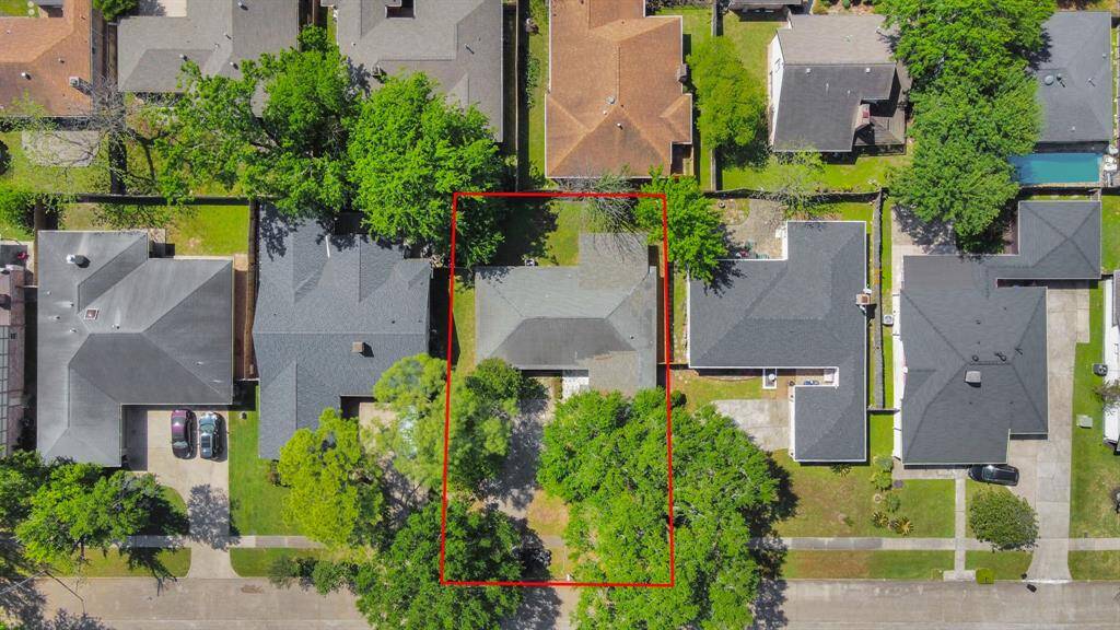 This aerial photo highlights a suburban property outlined in red. The home is centrally located on a tree-lined street, surrounded by neighboring houses with well-maintained yards. The area appears to be quiet and residential, offering a cozy neighborhood feel.