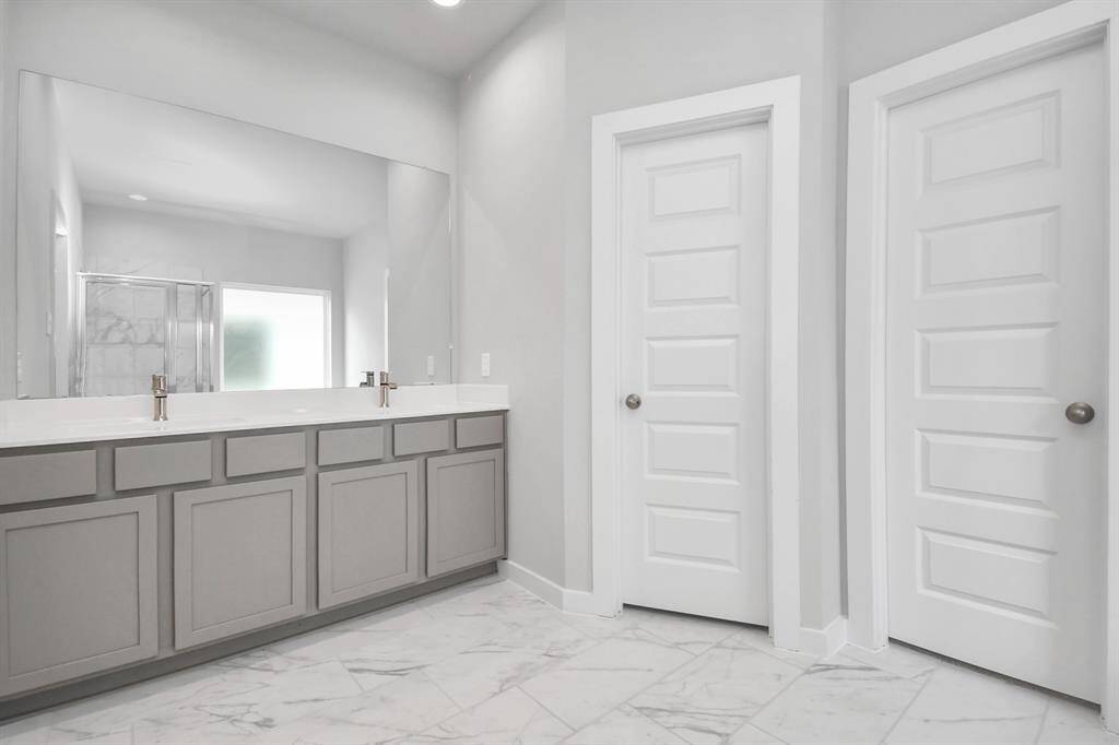 Escape to a spa-like oasis in this primary bathroom. Features elegant vanity with light countertops, modern hardware, and bright recessed lights. Sample photo of completed home with similar floor plan. Actual colors and selections may vary.