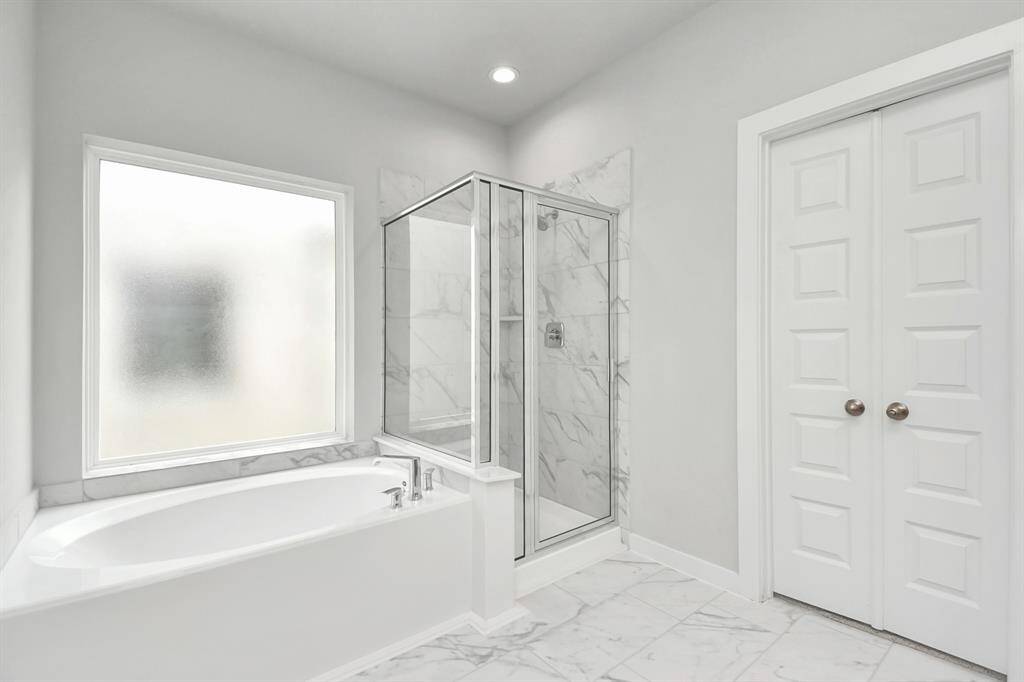 Enjoy a walk-in shower with tile surround, a separate garden tub with custom detailing. Sample photo of completed home with similar floor plan. Actual colors and selections may vary.
