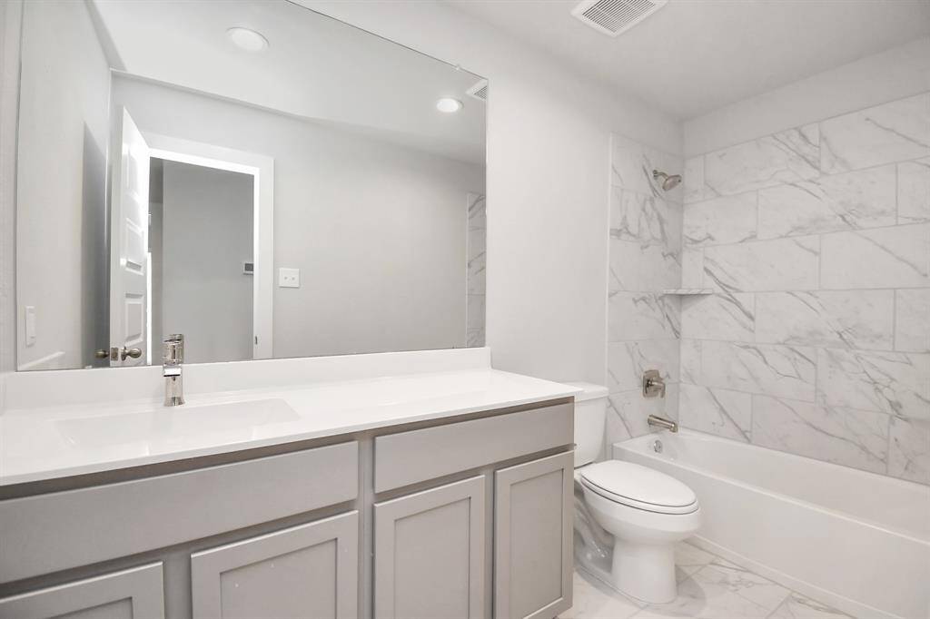 Sophistication in the secondary bathroom, where tile flooring complements a bath/shower combo with tile surround. Light wood cabinets complete with a beautiful light countertop, enhances the space for a truly inviting ambiance. Sample photo of completed home with similar floor plan. Actual colors and selections may vary.