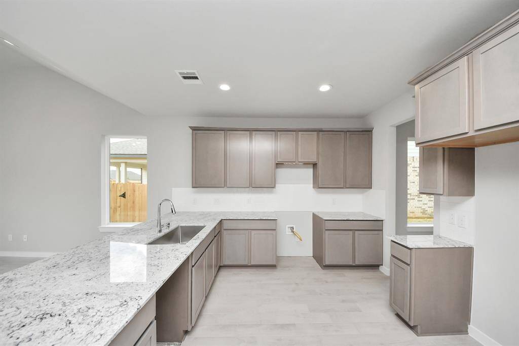 This kitchen is by far any chef’s dream! This spacious kitchen features high ceilings, dark stained wood cabinets, granite countertop, SS appliances (To be Installed), modern tile backsplash, recessed lighting, and extended counter space, all overlooking your huge family room. Sample photo of completed home with similar floor plan. Actual colors and selections may vary.