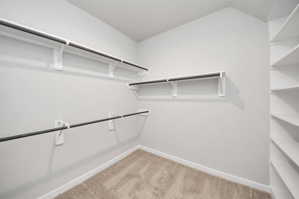 Walk-in closet that epitomizes luxury and practicality. This generously sizedspace features built-in shelving, offering abundant room for impeccableorganization. High ceilings and recessed lighting create a bright andwelcoming ambiance. Sample photo of completed home with similar floor plan. Actual colors and selections may vary.