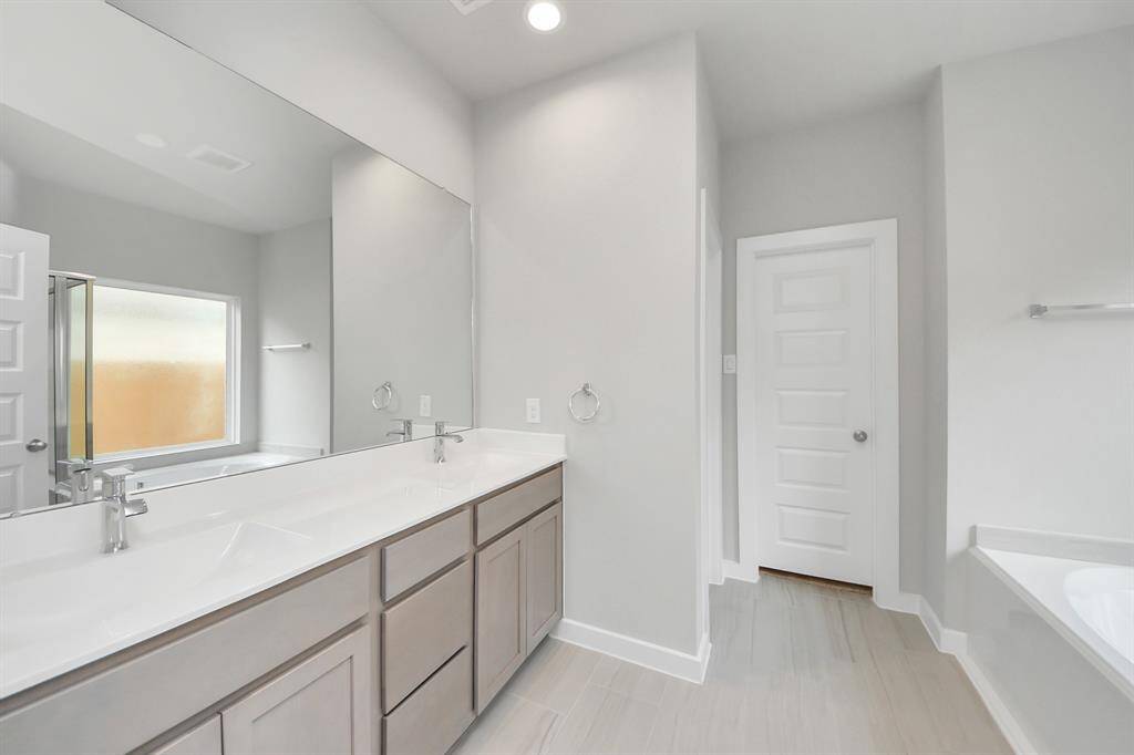 Escape to a spa-like oasis in this primary bathroom. Enjoy a walk-in showerwith tile surround, a separate garden tub with custom detailing, and an elegantvanity featuring light countertops, modern hardware, and beautiful recessed lights.Experience luxury and relaxation in every detail Sample photo of completed home with similar floor plan. Actual colors and selections may vary.