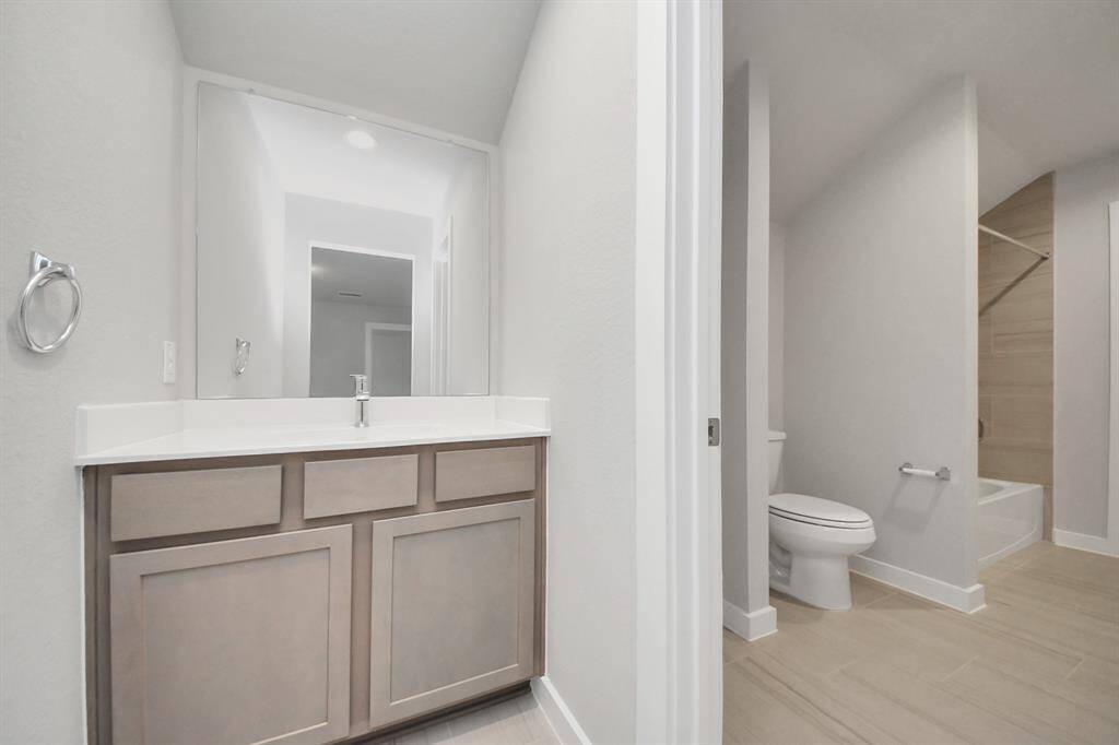 Experience convenience in the secondary bathroom, designed for Jack and Jillarrangements, now with a separate vanity area. This well-appointed spaceshowcases stylish tile flooring, a bath/shower combo with an elegant tilesurround, and light-stained wood cabinets. The beautiful light countertop adds atouch of sophistication, combining functionality and aesthetics seamlessly. Sample photo of completed home with similar floor plan. Actual colors and selections may vary.