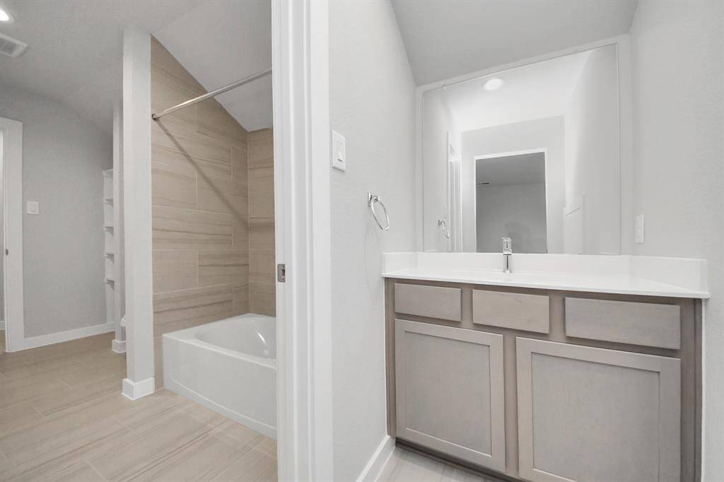 Experience convenience in the secondary bathroom, designed for Jack and Jillarrangements, now with a separate vanity area. This well-appointed spaceshowcases stylish tile flooring, a bath/shower combo with an elegant tilesurround, and light-stained wood cabinets. The beautiful light countertop adds atouch of sophistication, combining functionality and aesthetics seamlessly. Sample photo of completed home with similar floor plan. Actual colors and selections may vary.