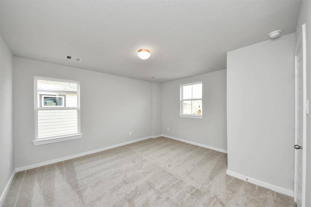 Secondary bedroom features plush carpeting, large windows that let in plenty of naturallight, bright paint, and spacious closets. Sample photo of completed home with similar floor plan. Actual colors and selections may vary.