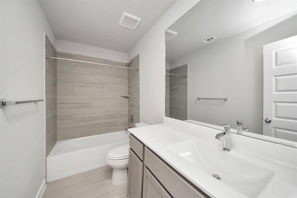 Secondary bath features tile flooring, bath/shower combo with tile surround, light stainedwood cabinets, beautiful light countertop. Sample photo of completed home with similar floor plan. Actual colors and selections may vary.