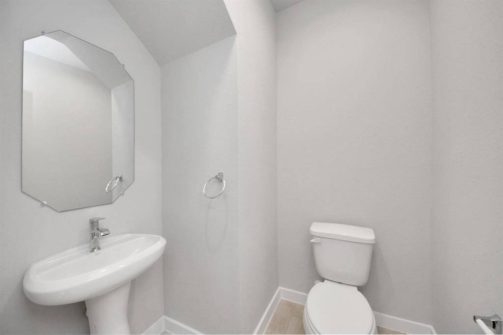 This half bathroom features a stylish pedestal sink, modern hardware, and bright recessedlighting, creating a sleek and inviting space. Sample photo of completed home with similar floor plan. Actual colors and selections may vary.