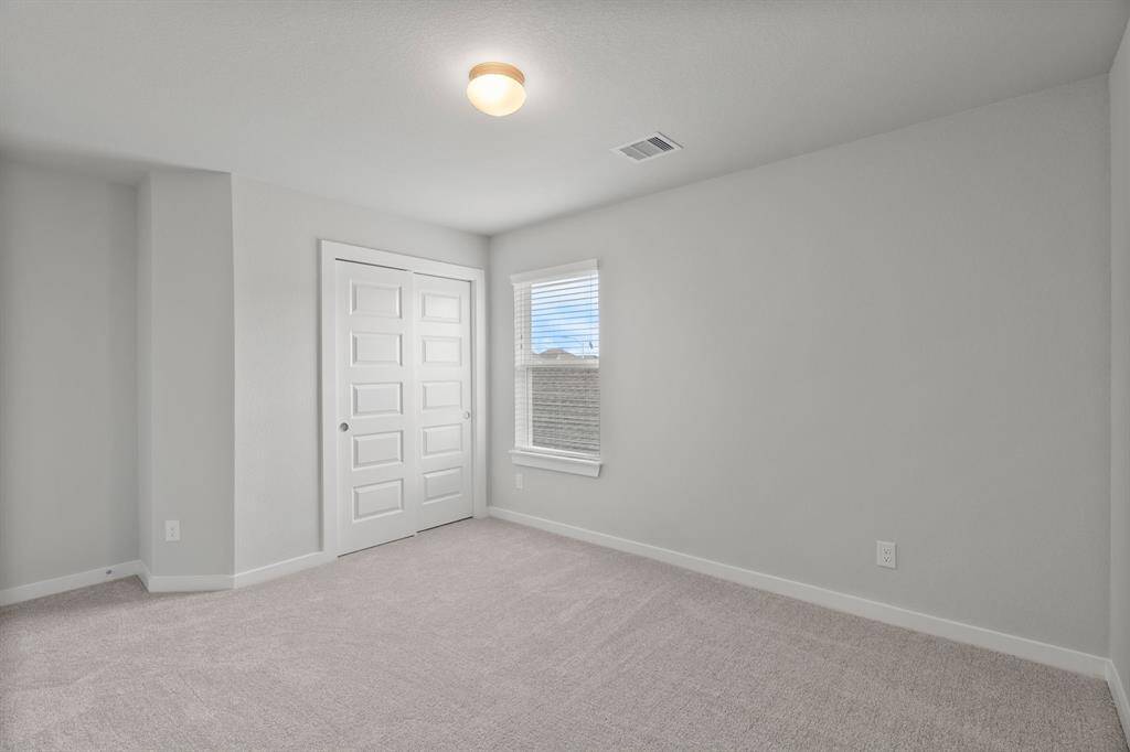 Secondary bedrooms feature elegant 5-panel doors with sleek, contemporary hardware that adds a touch of sophistication. Sink your feet into the plush, fluffy carpet that invites comfort and warmth. Large windows flood the space with an abundance of natural light, framed by privacy blinds that offer the perfect balance between openness and seclusion.Sample photo of completed home. As-built color and selections may vary.