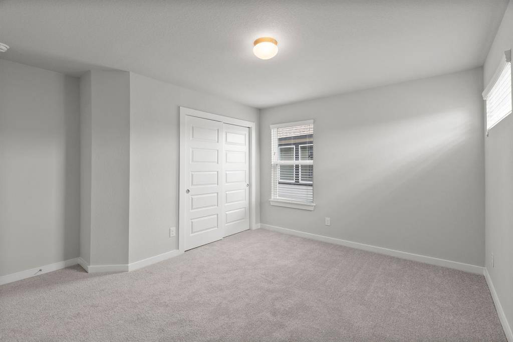 Secondary bedrooms feature elegant 5-panel doors with sleek, contemporary hardware that adds a touch of sophistication. Sink your feet into the plush, fluffy carpet that invites comfort and warmth. Large windows flood the space with an abundance of natural light, framed by privacy blinds that offer the perfect balance between openness and seclusion.Sample photo of completed home. As-built color and selections may vary. Sample photo of completed home. As-built color and selections may vary.