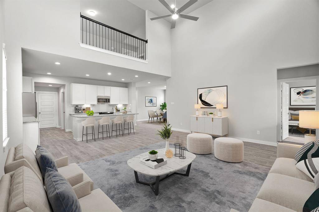 Bring your loved ones and guests together in the inviting living room! Boasting lofty high ceilings, recessed lighting, a stylish ceiling fan, custom paint, stunning flooring, and expansive windows that flood the space with ample natural light all day long. Sample photo of completed home. As-built color and selections may vary.