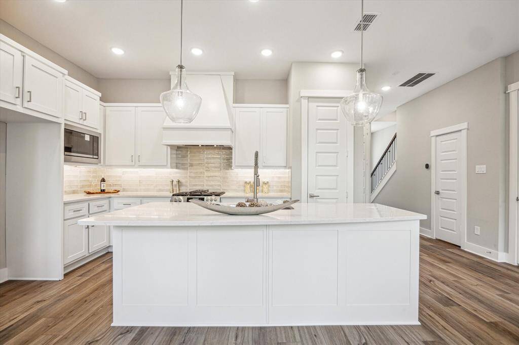 White Kent Moore cabinets with an upgraded vent hood cabinet, eat-in island with upgraded Silestone countertops