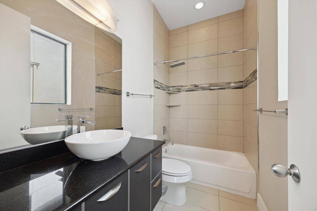 En-suite bathroom for the secondary bedroom featuring modern finishes, custom tile work, and plenty of storage.