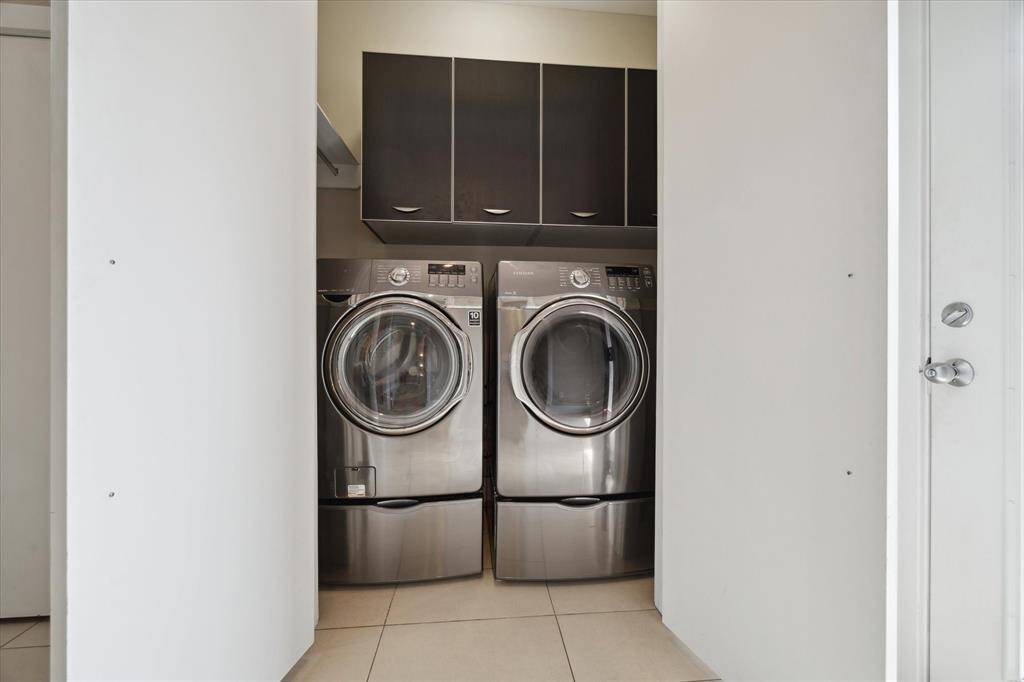 Utility room equipped with built-in cabinets, hanging rod, and included washer and dryer — combining convenience and functionality.