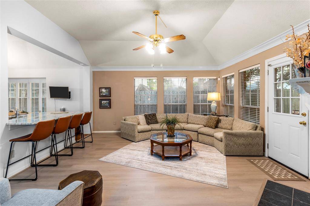 The living room features two walls of windows with blinds - perfect for letting in lots of light. It's a great open space for entertaining and includes a breakfast bar with four stools to augment the dining spaces.