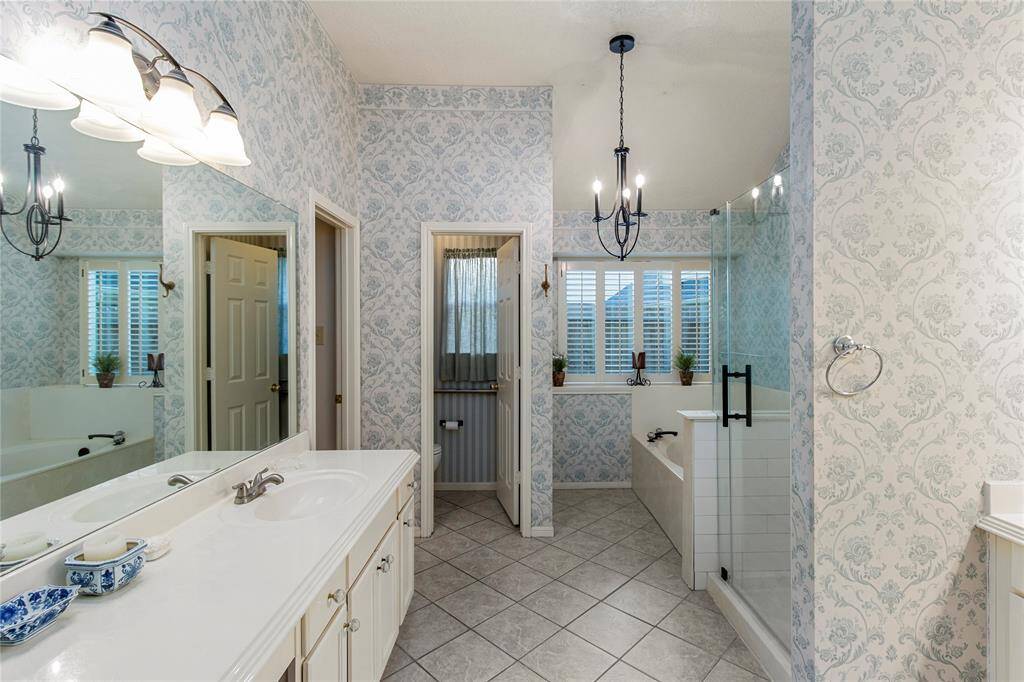 The primary bedroom features a spacious bathroom with a his and her sink and cabinets, a tiled shower with glass door, and large garden tub for soaking!