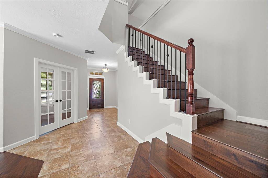 The front of the home features an office with glass inlay french doors and a beautiful hardwood staircase.