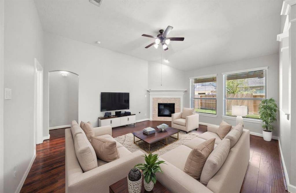 Family room with so much natural light, a gas log fireplace and warm hardwoods opens to the kitchen and breakfast area, virtually staged.
