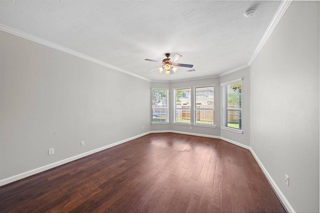 Large primary bedroom with warm hardwoods and natural light