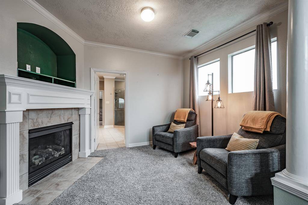 Cozy bedroom retreat featuring a charming fireplace sitting area.