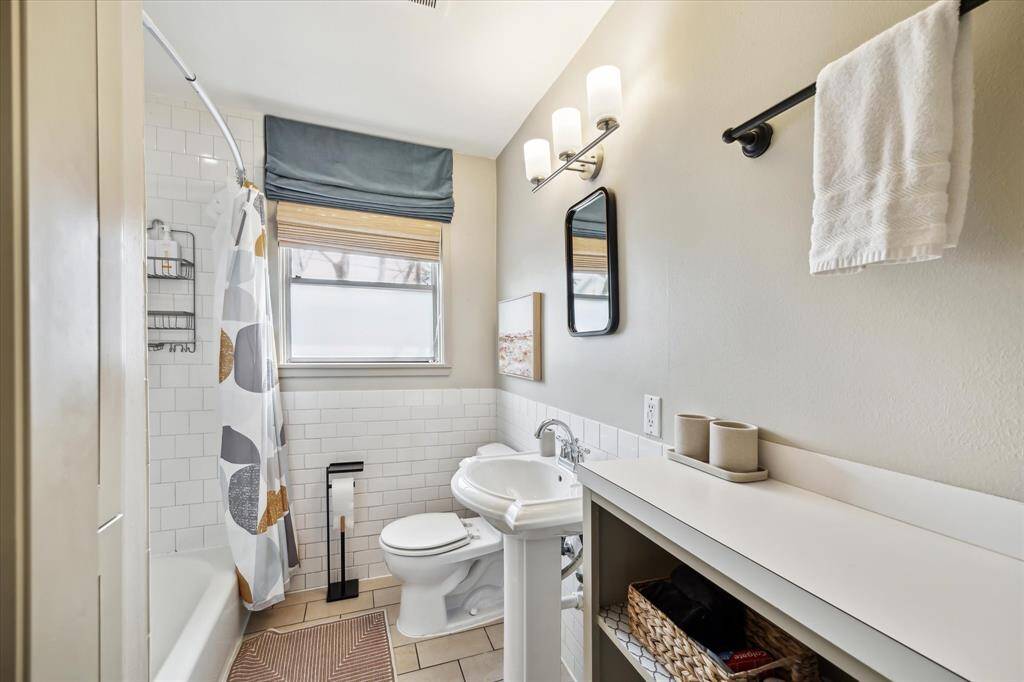Stylishly designed bathroom featuring a classic white subway tile, tub/shower, pedestal sink and built-in storage make this bath sparkle.