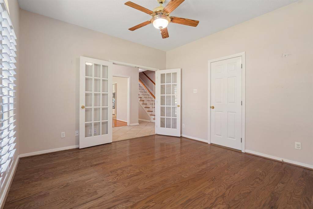 Bright room with hardwood floors, a ceiling fan, and French doors opening to the entry. Ideal for a home office or sitting area.