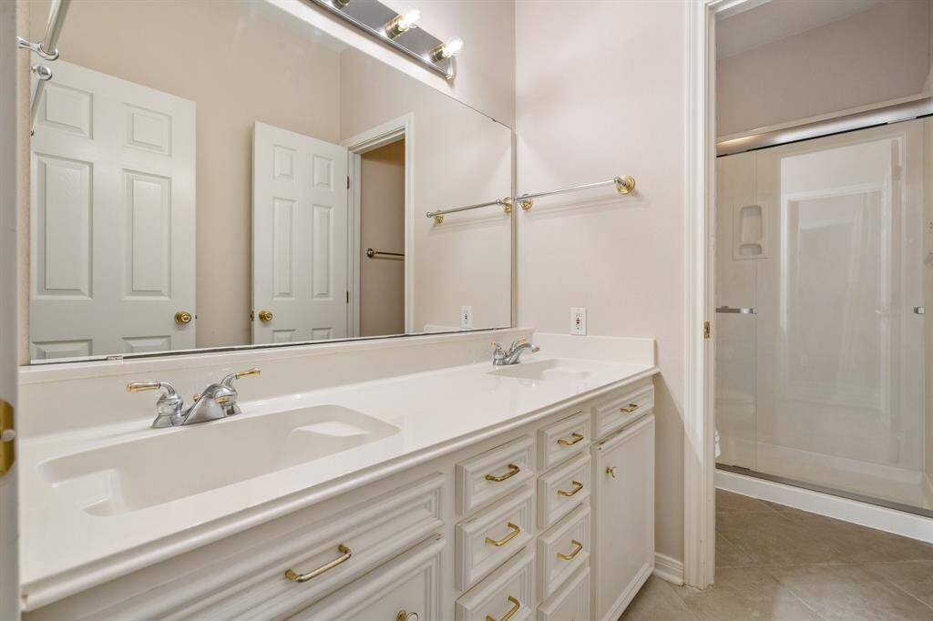 Third bathroom upstairs features a dual-sink vanity with ample storage, a large mirror, and a modern shower with a glass door. The neutral color palette and bright lighting create a clean, inviting space.