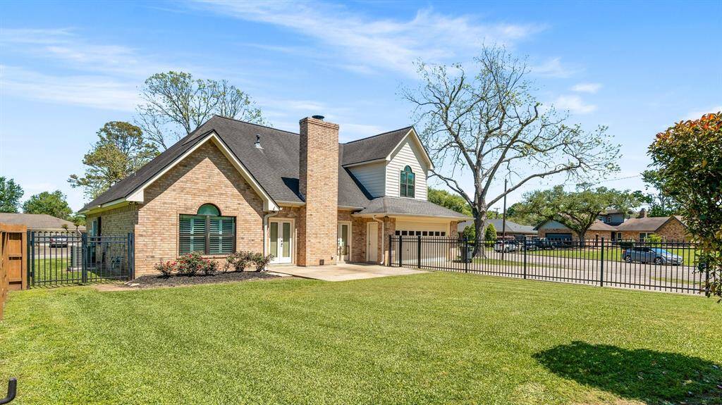 Lots of character in this charming brick home with a gabled roof and a large front yard. It features a two-car garage, a fenced perimeter, and well-maintained landscaping. The property is situated on a corner lot in a suburban neighborhood.