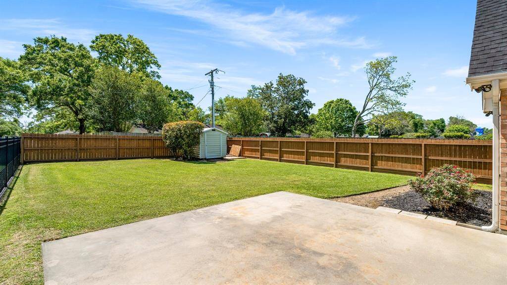 Roomy backyard with a neatly manicured lawn, privacy fence, and a small storage shed. Ideal for outdoor activities and gardening.